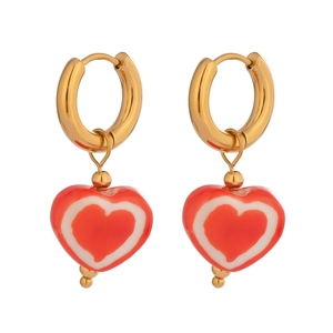 Gros plan de boucles d'oreilles créoles dorées avec pendentifs en cœur émaillé rouge