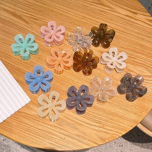 Set of 12 camellia flower hair claws in jelly colors on a wooden surface