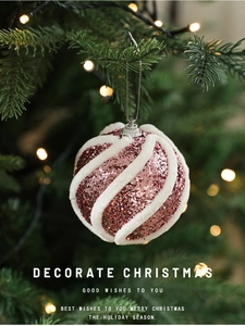 Rosa Weihnachtskugel mit Pailletten und weißen Plüschlinien am Weihnachtsbaum aufgehängt