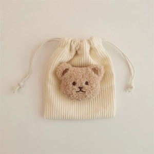Detailed view of cream corduroy drawstring pouch with a cute brown plush bear motif
