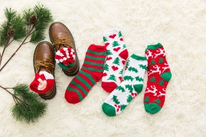 Close-up of cozy Christmas coral fleece socks with elk and tree patterns on white rug