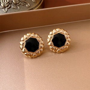 Macro shot of vintage gold earrings with black enamel inlay on a golden tray