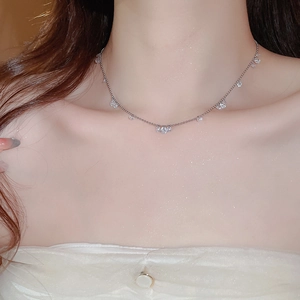 Detailed view of a silver necklace with sparkling zircon pendants on a model's neck