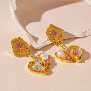 Detail of vintage gold earrings with pink rhinestones, faux pearls and crystals
