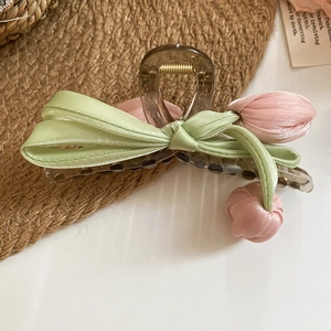 Detailed view of acrylic flower hair claw with green silk bow and pink fabric tulips