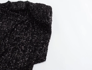Detailed view of high-density black sequins sewn on a sophisticated evening dress fabric