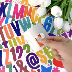 Applying a waterproof orange vinyl letter P sticker to a white ceramic mug for decoration