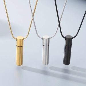 Detailed view of three cylindrical stainless steel pendant necklaces in gold, silver, and black