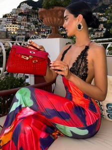 Close-up of a red crocodile pattern handbag with elegant metal lock and lace dress detail