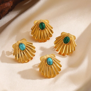 Golden shell earrings with malachite and turquoise stones on elegant beige satin fabric
