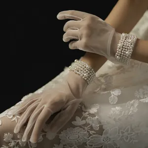 Detailed view of white sheer bridal gloves with elegant multi-layer pearl wrist cuffs