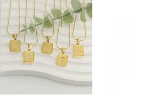 Détail des pendentifs lettres en acier inoxydable doré sablé sur chaînes serpent