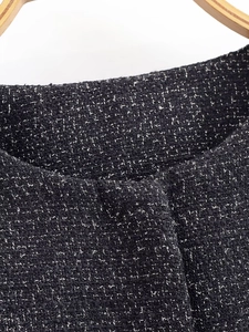 Close-up of black and white tweed fabric texture on a jacket with a wooden hanger