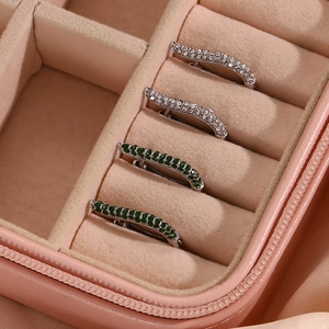 Detail of silver hoop earrings with white and green zircon stones in a pink jewelry box