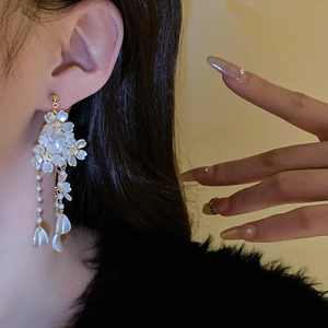 Détail de longues boucles d'oreilles fleur à pompons perles sur un mannequin
