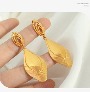 Macro detail of elegant gold leaf earrings with brushed finish and textured edges