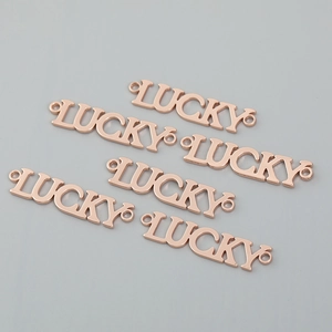 Macro shot of five rose gold metal LUCKY charms with double rings for DIY jewelry