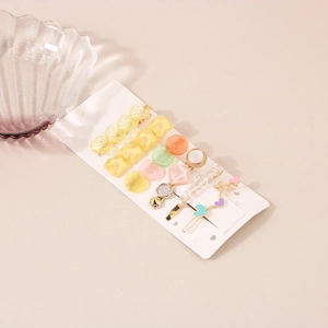 Détail d'un lot de 6 barrettes avec perles et strass sur une carte d'affichage