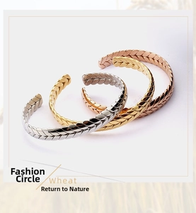 Close-up of three-tone wheat chain open bangles in gold, silver, and rose gold finish