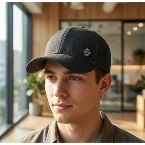Détail d'une casquette de baseball gris foncé avec logo JEANS en métal sur tissu denim