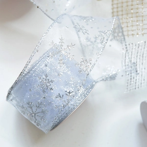 Macro shot of light blue sheer ribbon with silver glitter snowflake patterns and metallic edges