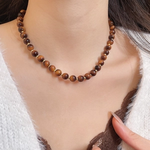 Detailed view of tiger eye bead necklace with gold spacers on a model neck