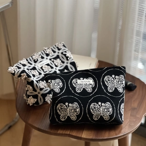 Gros plan détaillé de la broderie papillon et florale sur des trousses de maquillage en toile