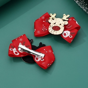 Detail of festive red Christmas bow hair clips with reindeer print and metal alligator grip