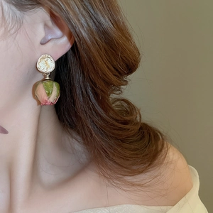 Close-up of model wearing gold-plated stainless steel floral earrings with resin flower