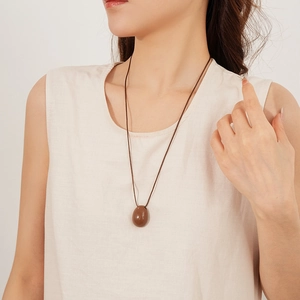 Collier à pendentif ovale minimaliste avec cordon marron porté par un mannequin