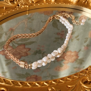 Détail d'un collier vintage en perles baroques avec chaîne dorée sur un miroir