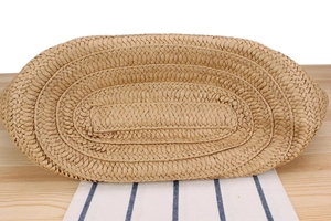 Detailed view of the oval woven base of the straw tote bag on a wooden table