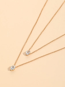 Detail of layered gold-tone necklace featuring teardrop cubic zirconia pendants