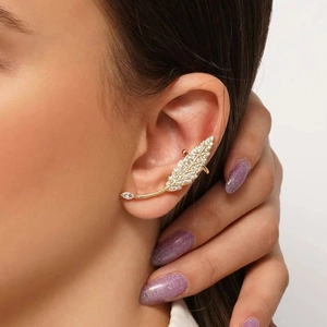 Detailed view of a gold feather ear cuff set with shimmering white zircons on a model