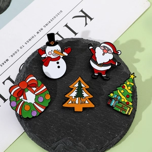 Detailed view of five Christmas enamel pins including Santa and Snowman on a stone coaster