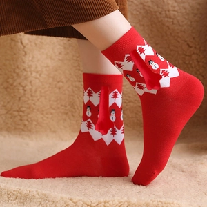 Detail of red Christmas socks with magnetic hands, festive tree patterns and 3D red nose