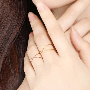 Close-up of minimalist crisscross stackable rings in 18k gold and rose gold finishes