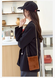 Detailed view of brown plush crossbody bag with golden chain strap on model