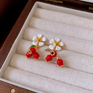 Detail shot of vintage floral earrings with red berry drops in a velvet jewelry box