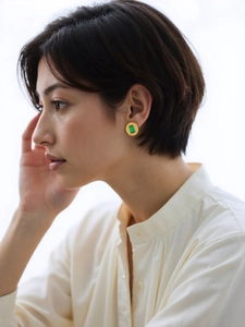 Mannequin portant des boucles d'oreilles dorées avec zircon vert rectangulaire et vis
