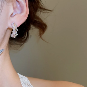 Close-up of minimalist C-shaped earrings with pink and clear crystal cluster details