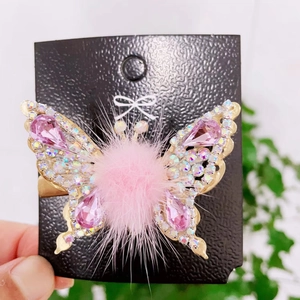 Detail of a moving butterfly hair clip with pink faux crystals and golden wing details