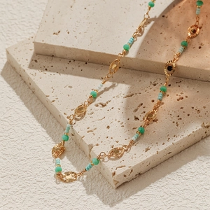 Detail of bohemian beaded necklace with turquoise stones on textured stone background