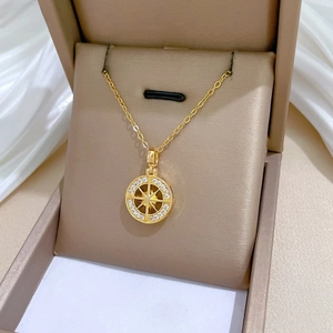 Detail of gold starburst compass pendant with crystal inlay on a silk background