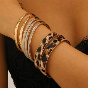 Close-up of stacked leopard print and hammered gold bangles with glitter details