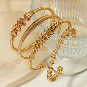 Lot de quatre bracelets joncs dorés en acier inoxydable au design torsadé et géométrique