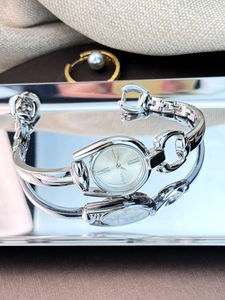 Macro close-up of a silver watch with horseshoe-shaped buckle links and Roman numerals