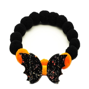 Detail of Halloween pet collar with orange pom-poms and a glittery black bat bow