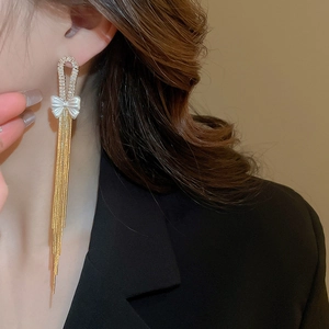 Close-up of elegant gold bow tassel earrings with zircon inlay worn by a model