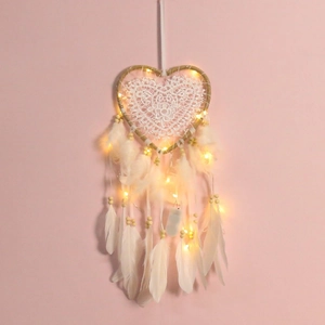 Capteur de rêves blanc en forme de cœur avec lumières LED et plumes sur fond rose